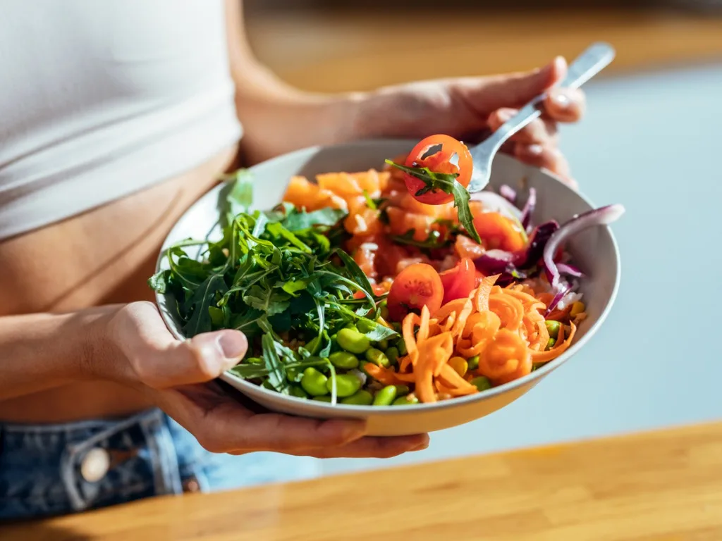 fitness woman eating a healthy poke bowl in the kitchen at home