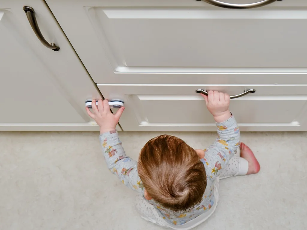 toddler baby boy rips off a cabinet drawer with his hand the child holds the cabinet door