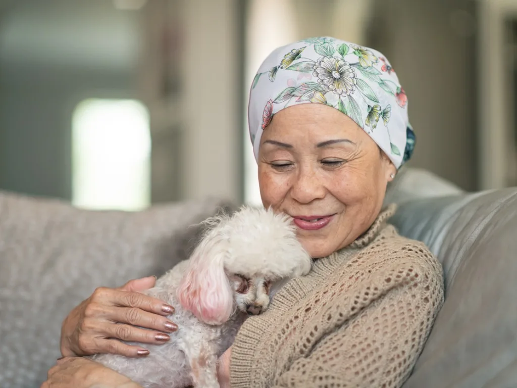 woman with cancer relaxes at home with her pet dog